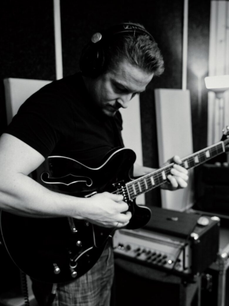 Alexander Stakenburg playing a semi-hollow electric guitar in a studio